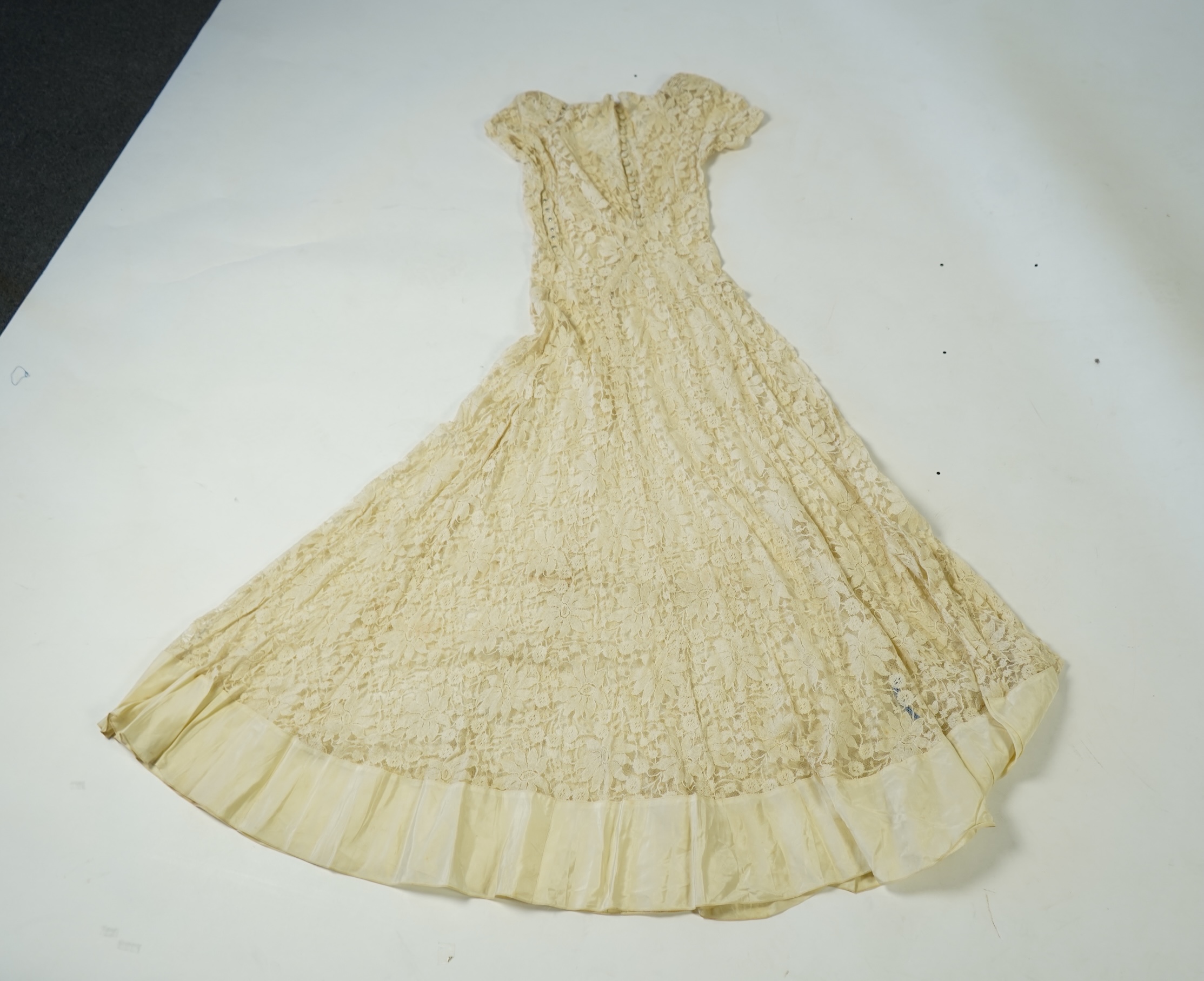 An early 1940's cream cotton lace and taffeta evening dress, with matching taffeta petticoat, possibly worn as a wedding dress., Dress 144cm long. Condition - minor repairs needed to lace in places and laundering to remo